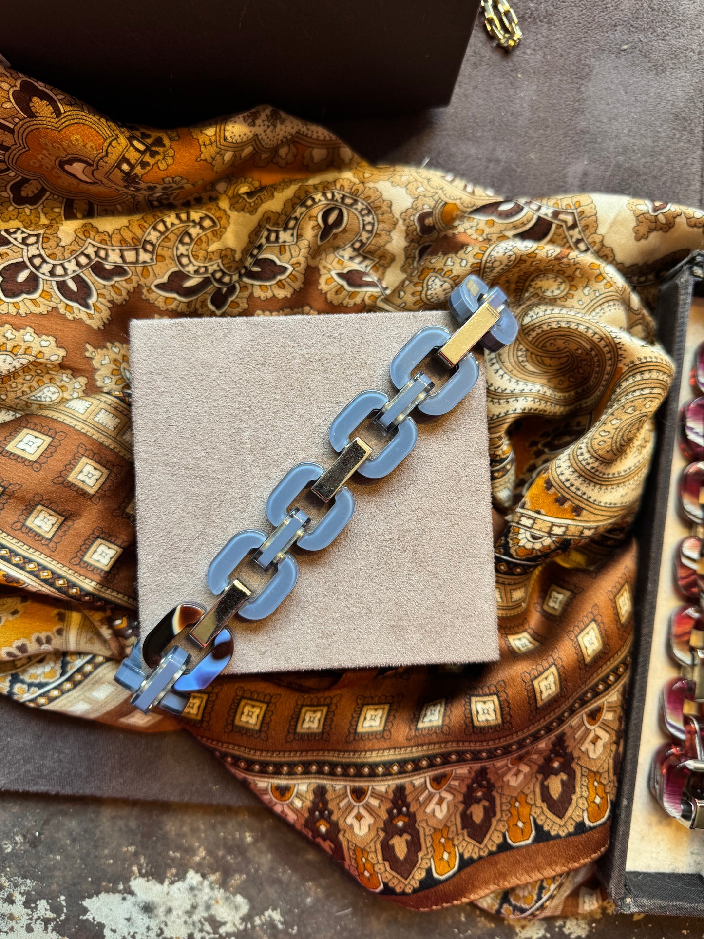 Grey blue chain bracelet with patterned link in a tortoise shell style.