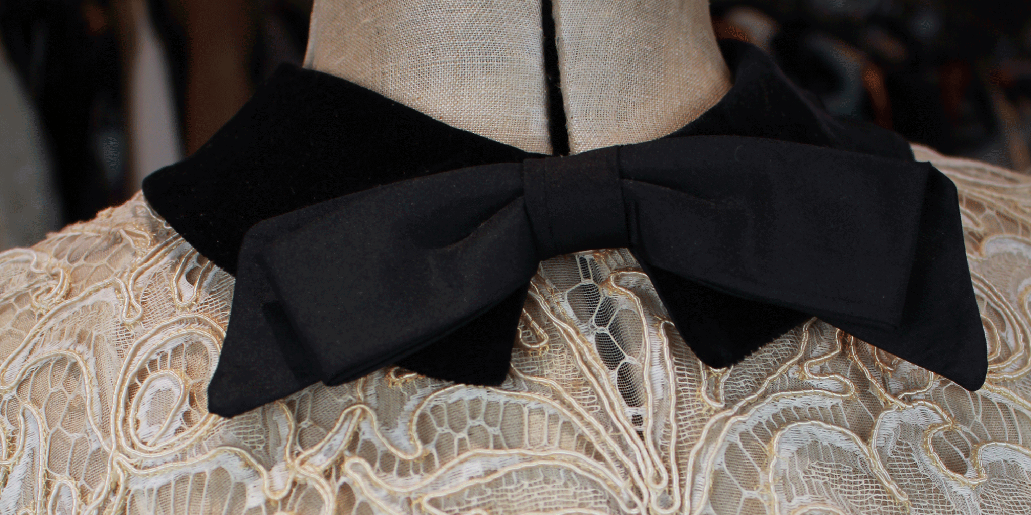 Details of a vintage Christian Dior iconic lace dress with a black bow collar neckline on an old hessian mannequin.
